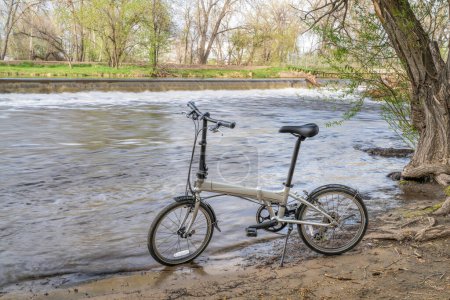 Foto de Bicicleta plegable ligera en una orilla del río Poudre en Fort Collins, Colorado, paisaje de primavera - Imagen libre de derechos