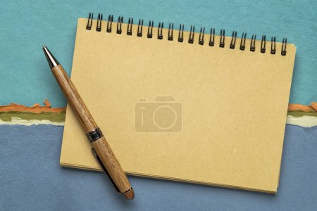 Photo for Blank spiral sketchbook with a pen against colorful abstract landscape - Royalty Free Image