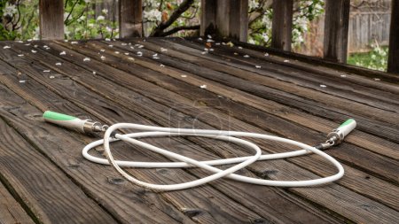 Foto de Cuerda de salto de fitness pesado en un rústico, cubierta del patio trasero de madera envejecida en el paisaje de primavera - Imagen libre de derechos