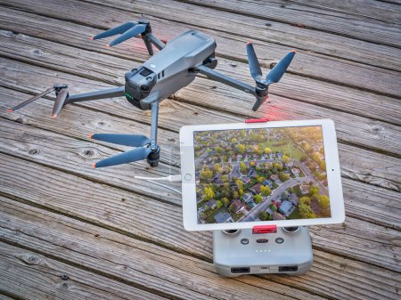 Photo for Fort Collins, CO, USA - December 1, 2021:  Mavic 3, an advanced foldable quadcopter drone by DJI on a rustic wooden deck with radio controller and ipad tablet displaying an aerial cityscape picture. - Royalty Free Image