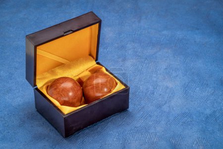Photo pour Une paire de boules de médecine chinoise en bois dans une boîte sur papier texturé - image libre de droit
