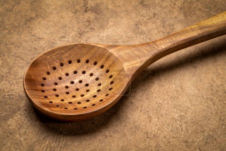 Photo for Drainer spoon - wooden kitchen cooking utensils on textured bark paper - Royalty Free Image
