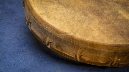 Photo for Detail of handmade, native American style, shaman frame drum against textured blue paper - Royalty Free Image