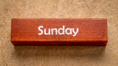 Photo for Sunday text on wooden block against handmade bark paper in earth tones, calendar concept - Royalty Free Image