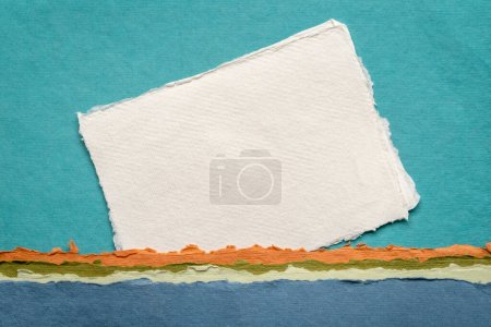Foto de Pequeña hoja de blanco blanco papel de trapo Khadi de la India contra el paisaje abstracto en tonos azules - Imagen libre de derechos