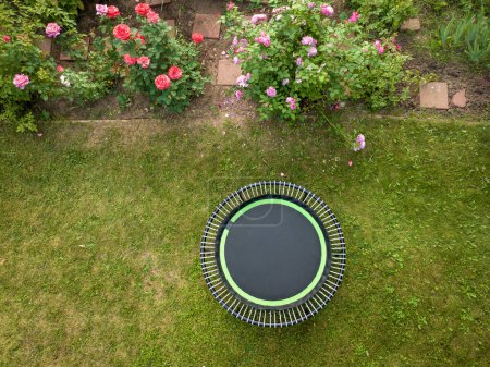 Téléchargez les photos : Mini trampoline pour l'exercice de fitness et le rebond dans une cour arrière, vue aérienne en été - en image libre de droit