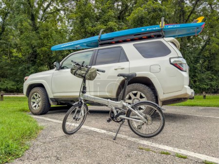 Téléchargez les photos : Rocheport, MO, États-Unis - 3 août 2023 : Dahon Mariner vélo pliant et Toyota 4Runner SUV avec une planche à pagaie debout sur les supports de toit à un parking de Katy Trail. - en image libre de droit