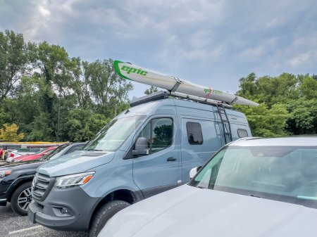 Photo for St Charles, MO, USA - August 4, 2023: Winnebago Revel camper van on Mercedes Sprinter chassis with Epic kayak or surfski on roof racks parked among other cars. - Royalty Free Image