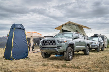Téléchargez les photos : Loveland, CO, États-Unis - 25 août 2023 : Tente de douche privée pop-up et camion Toyota Tacoma avec une tente de toit stationnée sur un terrain de camping occupé. - en image libre de droit