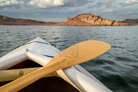 Photo for Bow of a decked expedition canoe with wooden paddle on a mountain lake, paddler view - Horsetooth Reservoir in northern Colorado - Royalty Free Image