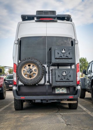 Téléchargez les photos : Loveland, CO, USA - 26 août 2023 : Retour du conteur Overland Mode LT, camping-car 4x4 basé sur le châssis Ford Transit avec un pneu de rechange et un rack avec différents engrenages attachés. - en image libre de droit