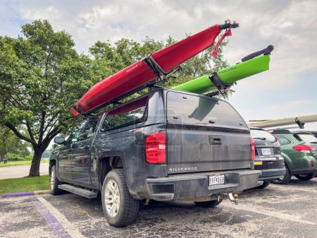 Foto de St Charles, MO, Estados Unidos - 4 de agosto de 2023: Kayaks en portaequipajes de Chevy Silverado con casquillo Leer estacionado entre otros coches. - Imagen libre de derechos