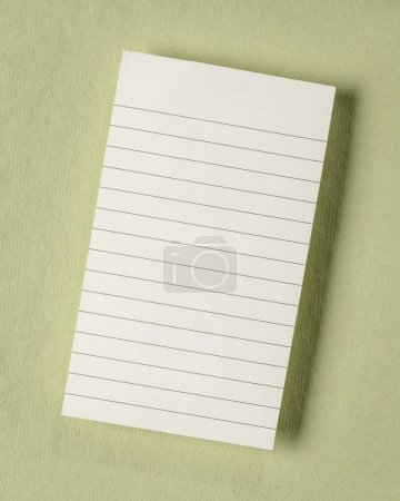 Photo for Small blank sheet of ruled paper against green textured background - Royalty Free Image