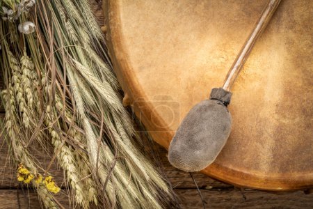 Foto de Hecho a mano, estilo americano nativo, tambor de marco de chamán con un batidor y ramo de flores silvestres secas y tallos de grano - Imagen libre de derechos