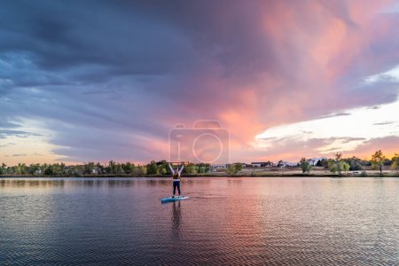 Photo for Lonely stand up paddler on a lake in Colorado at dusk with dramatic sunset clouds - Royalty Free Image