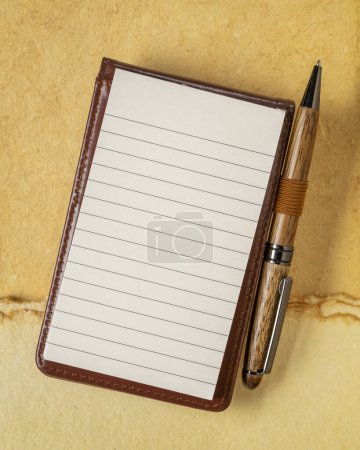 Téléchargez les photos : Feuille vierge de papier gouverné dans un petit journal avec un stylo de luxe contre du papier d'art texturé - en image libre de droit