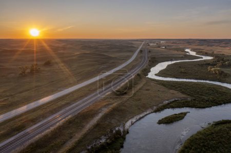Téléchargez les photos : Lever de soleil sur une rivière serpentant à travers les collines de sable du Nebraska, l'autoroute et le chemin de fer - vue aérienne de la rivière Middle Loup près de Halsey - en image libre de droit