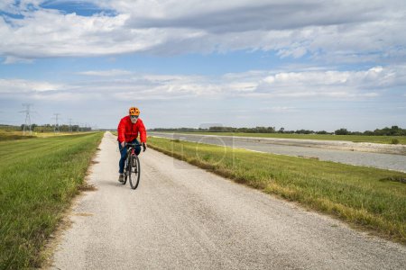 Photo for Senior athletic man is riding a gravel touring bike - biking on a levee trail along Chain of Rocks Canal near Granite City in Illinois - Royalty Free Image