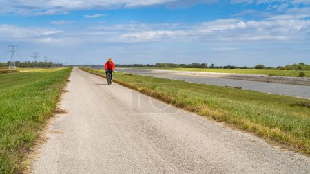 Foto de Ciclista solitario está montando una bicicleta de grava de turismo en bicicleta en un sendero dique a lo largo de Chain of Rocks Canal cerca de Granite City en Illinois - Imagen libre de derechos