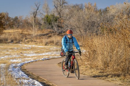 Téléchargez les photos : Cycliste masculin sénior fait du vélo de gravier de randonnée sur une piste cyclable à Fort Collins, Colorado par temps froid d'automne avec un peu de neige - en image libre de droit