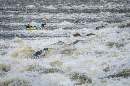 Photo for Granite City, Il, USA - October 8, 2023: Two whitewater kayakers playing and training below Low Water Dam on the Mississippi River at Chain of Rocks near St Louis, Missouri. - Royalty Free Image