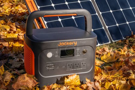 Téléchargez les photos : Fort Collins, CO, États-Unis - 5 novembre 2023 : La centrale électrique portative Jackery Explorer 1000 Plus est chargée par un panneau solaire dans un champ recouvert de feuilles d'érable sèches. - en image libre de droit