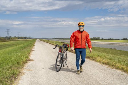 Téléchargez les photos : Cycliste senior athlétique avec un vélo de randonnée en gravier sur un chemin de levée le long de la chaîne de Rocks Canal près de Granite City dans l'Illinois - en image libre de droit