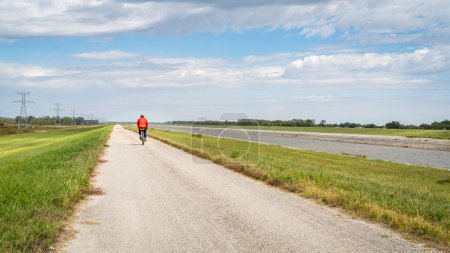 Photo for Lonely cyclist is riding a gravel touring bike - biking on a levee trail along Chain of Rocks Canal near Granite City in Illinois - Royalty Free Image