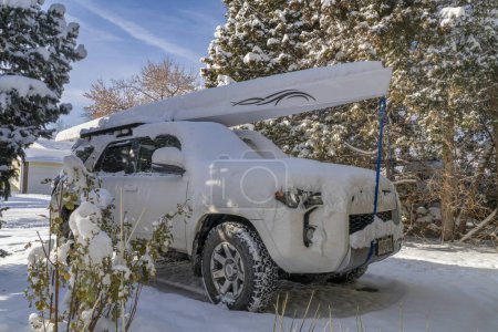 Photo for Fort Collins, CO, USA - November 25, 2023: Toyota 4runner SUV with a rowing shell, LiteRace 1x by Liteboat on roof racks covered by snow in a driveway. - Royalty Free Image