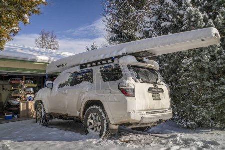 Téléchargez les photos : Fort Collins, CO, USA - 25 novembre 2023 : Toyota 4runner SUV with a rowing shell, LiteRace 1x by Liteboat on roof racks covered by snow in a driveway. - en image libre de droit