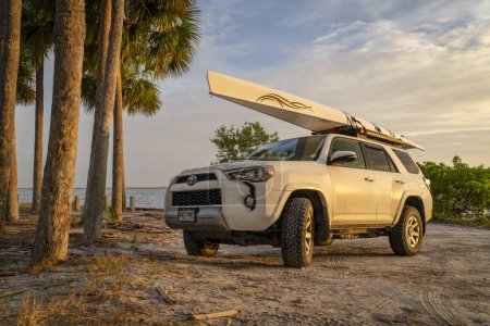 Foto de Skyway Beach, FL, Estados Unidos - 22 de noviembre de 2023: Toyota 4runner SUV with a rewing shell, LiteRace 1x by Liteboat on roof racks on a Florida beach. - Imagen libre de derechos