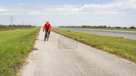 Téléchargez les photos : Senior athlétique est sur un vélo de randonnée en gravier vélo sur un chemin de levée le long de la chaîne de Rocks Canal près de Granite City dans l'Illinois - en image libre de droit