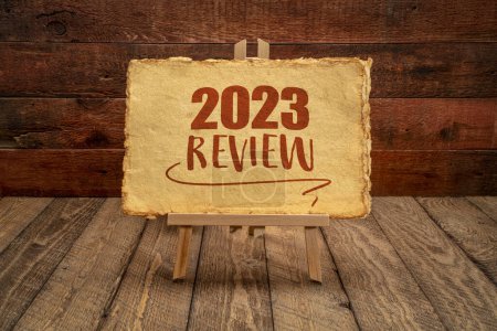 2023 year review - easel sign with antique paper against rustic wood, end of year business concept
