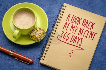 Foto de Una mirada retrospectiva a mis últimos 365 días - una nota en un cuaderno en espiral con café, reseña retrospectiva de fin de año - Imagen libre de derechos