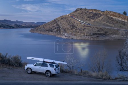 Téléchargez les photos : Fort Collins, CO, USA - 21 décembre 2023 : Toyota 4runner SUV with a rowing shell, LiteRace 1x by Liteboat on roof racks on a shore of Horsetooth Reservoir - fall or winter dusk scenery. - en image libre de droit