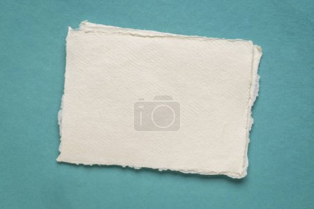 Foto de Pequeña hoja de papel de trapo blanco Khadi en blanco de la India contra el papel de arte azul - Imagen libre de derechos