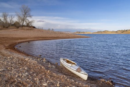 Téléchargez les photos : Canot d'expédition ponté avec une pagaie en bois sur une rive rocheuse du réservoir Horsetooth dans le nord du Colorado dans des paysages de saison froide - en image libre de droit