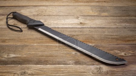 Photo for Bush clearing machete with carbon steel blade and saw against rustic wooden deck - Royalty Free Image