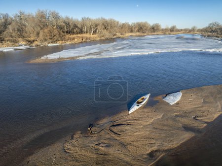 Foto de Canoa de expedición cubierta en un banco de arena con témpano de hielo - South Platte River en el este de Colorado - Imagen libre de derechos