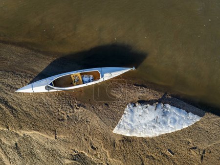 Photo for Decked expedition canoe on a sandbar with ice floe - South Platte River in eastern Colorado - Royalty Free Image