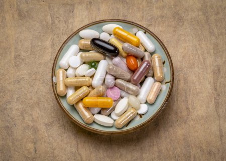 Foto de Desayuno para un adicto suplemento - píldoras vitamínicas, cápsulas y tabletas en un tazón pequeño - estilo de vida saludable, sobredosis o concepto de adicción - Imagen libre de derechos