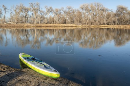 Téléchargez les photos : Planche à pagaie gonflable debout sur un lac au début du printemps - étangs Prospect, l'une des zones naturelles le long de la rivière Poudre à Fort Collins, Colorado - en image libre de droit