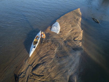 Téléchargez les photos : Pagayeur mâle avec un canot d'expédition ponté sur un banc de sable avec banquise - South Platte River dans l'est du Colorado - en image libre de droit