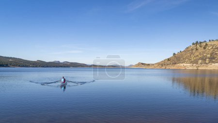 Téléchargez les photos : Rameur solitaire dans une coquille d'aviron côtière - Carter Lake en automne ou en hiver dans le nord du Colorado. - en image libre de droit