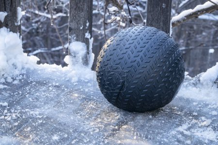 Téléchargez les photos : Lourde, 50 lb, boule de slam rempli de sable sur un pont arrière glacé, exercice et concept de fitness fonctionnel - en image libre de droit