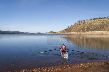Téléchargez les photos : Rameur mâle sénior ramant une coquille d'aviron côtière - Carter Lake en automne ou en hiver dans le nord du Colorado. - en image libre de droit