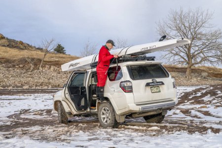 Photo for Loveland, CO, USA - February 6, 2024: Senior rower is loading Liteboat rowing shell on roof racks of Toyota 4Runner SUV on a shore of Carter Lake in northern Colorado in winter scenery. - Royalty Free Image