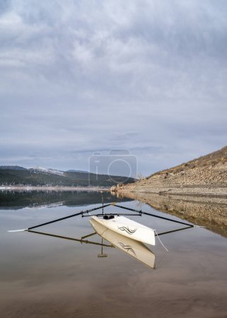 Téléchargez les photos : Loveland, CO, USA - 6 février 2024 : Coquille d'aviron côtière, Literace 1x by Liteboat, avec un miroir et un sac imperméable sur une rive du lac Carter dans le nord du Colorado dans un paysage hivernal. - en image libre de droit