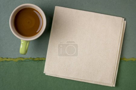 Téléchargez les photos : Serviette vierge avec une tasse de café contre paysage abstrait de papier vert - en image libre de droit