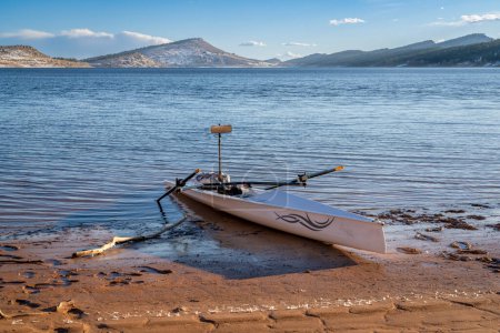 Téléchargez les photos : Loveland, CO, USA - 8 février 2024 : Coquille d'aviron côtière, Literace 1x by Liteboat, avec un miroir et un sac imperméable sur une rive du lac Carter dans le nord du Colorado dans un paysage hivernal. - en image libre de droit